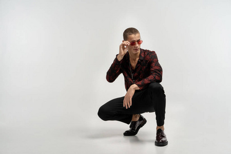 穿着休闲的穿黑色牛仔裤的年轻人蹲着摆姿势照片