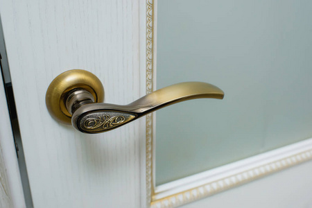 门漆成白色。 门上的金色装饰品。 木质纹理。 房间间的门。 铁门铰链。 青铜色的门把手。