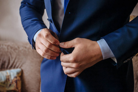 穿西装的时髦男人系上纽扣,挺直夹克准备出门. 准备婚礼照片