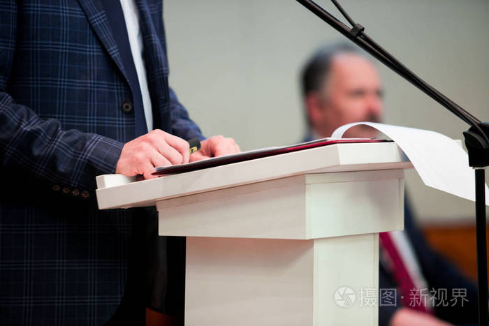 男演讲者看着房间,对着麦克风说,在会议上讲话