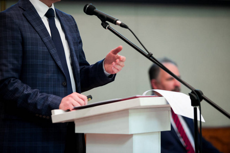 男演讲者看着房间,对着麦克风说,在会议上讲话照片