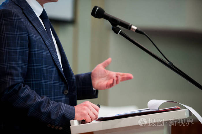 男演讲者看着房间,对着麦克风说,在会议上讲话