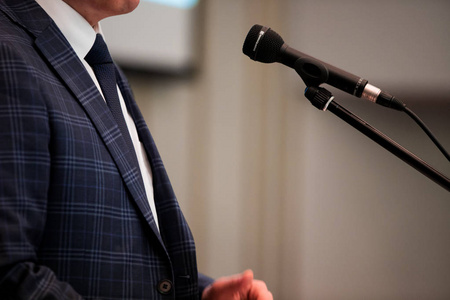 男演讲者看着房间,对着麦克风说,在会议上讲话照片