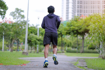 年轻的健身男子在公园户外散步,跑步者在外面的路上跑步,亚洲运动员在