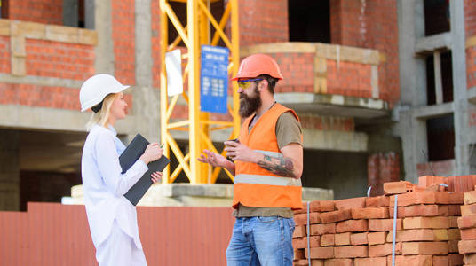 建筑客户与建筑行业参与者之间的关系。施工团队沟通理念。妇女工程师和残酷的建设者沟通建筑工地背景