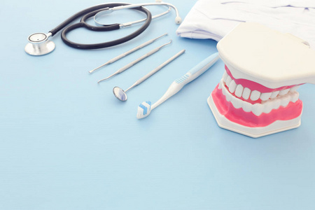 牙科保健工具用于牙科和塑料牙齿模型在诊所。木制蓝色背景