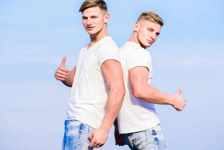 拥有相同的孪生兄弟的好处和缺点。 男人双胞胎兄弟肌肉男穿白色衬衫天空背景。 兄弟情谊概念。 有双胞胎兄弟的好处。 兄弟的友谊。