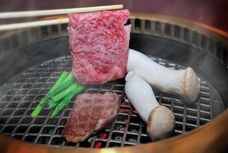 在木炭火中用筷子烤日本牛肉。