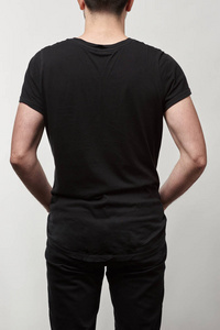 黑色T恤男子的背面视图，复制空间隔离在灰色上