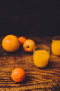健康水果，包括橘子葡萄水果和苹果，散落在木桌上，带有果汁眼镜，具有维生素和良好营养的概念