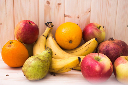 各种水果，苹果，香蕉，橘子，石榴，天然木背景。 健康食品