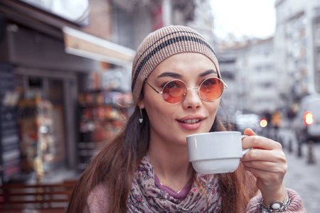 年轻的肖像女士在户外喝咖啡