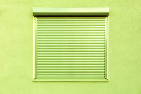 保护浅绿色房子正面的窗户上有浅绿色的金属百叶窗.照片