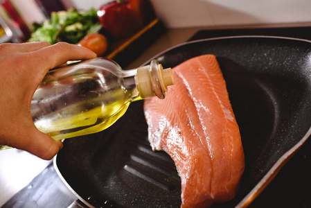 生三文鱼片在锅里煮，把橄榄油倒在上面煮。