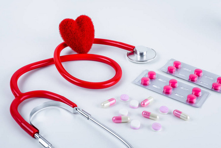 红色心脏和听诊器药物药片在白色桌子上，有复制空间