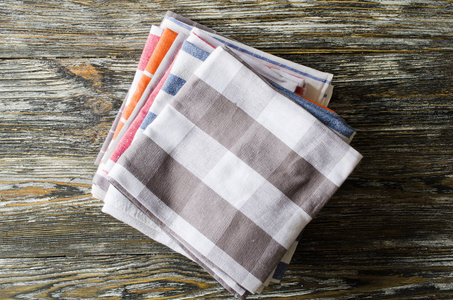 一叠厨房毛巾或餐巾纸放在乡村木桌上。 上面的视图和复制空间