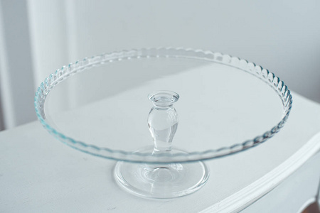 白色桌子上的玻璃蛋糕支架，白色背景隔离