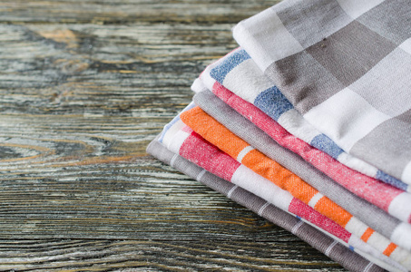 一叠厨房毛巾或餐巾纸放在乡村木桌上。 上面的视图和复制空间
