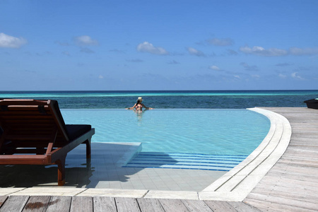 戴帽子的漂亮女人在酒店游泳池放松。 热带天堂。