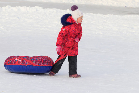一个女孩坐在雪地里的充气雪橇上