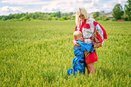 一个金发女人和她的儿子，穿着和服，亲切地拥抱谷物领域。