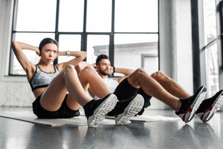 年轻夫妇在健身房的瑜伽垫上做腹肌锻炼