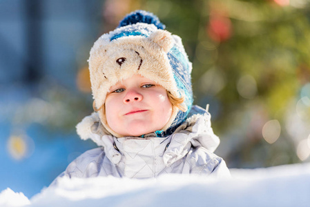 在雪地里玩耍时穿着一件棉袄和一顶针织帽子，玩得很开心。