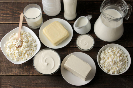 奶制品。牛奶，酸奶油，奶酪，黄油和干酪放在棕色的木桌上。顶部视图