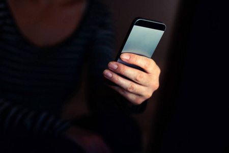 在暗室内部使用手机发短信的女人,随手打短信照片