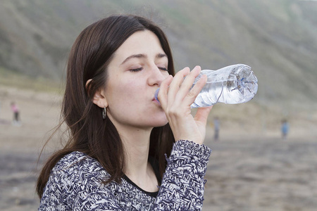 一个女孩从瓶子里喝淡水
