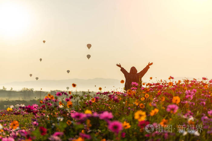 生活方式旅行者女性举起手,感受良好的放松和快乐的自由,并在日出的
