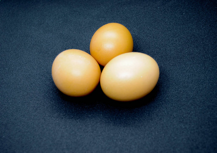 黑色背景上有三个棕色的鸡蛋。 照片适合关于食物和健康的故事。