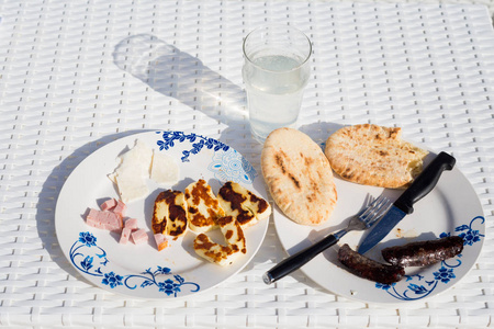 沃罗克利尼当地餐厅的哈洛米火腿葡萄酒香肠和皮塔面包早餐。 塞浦路斯岛上的传统塞浦路斯食物。
