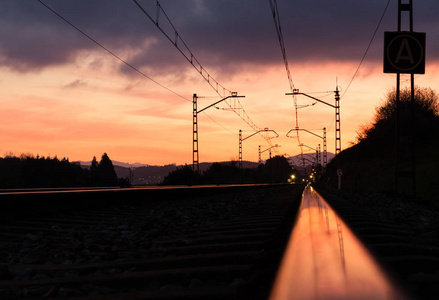 日落时火车站顶着美丽的天空。 工业景观，铁路，彩色蓝天，红云，太阳