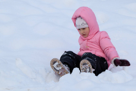 一个穿粉色夹克的女孩在冬天的雪地里玩耍