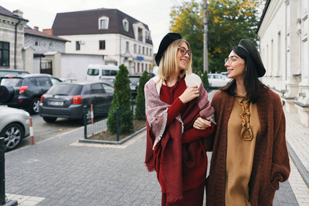 无忧无虑的时尚女性模特穿着优雅的秋装和眼镜。 年轻的时尚女孩穿着时尚的编织羊毛衣服和帽子，在城市背景秋季肖像。