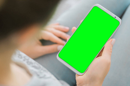 妇女的手拿着色度键手机。绿色屏幕智能手机。模拟图像。特写