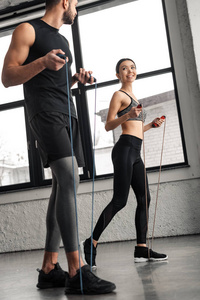 年轻人和女人用跳绳锻炼身体，在健身房互相微笑