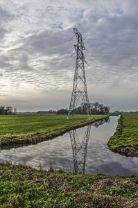 高压尼龙反射在草原之间的沟渠中，在荷兰德尔夫特以南的密登德尔夫兰开阔的圩田景观中，在戏剧性的天空下