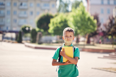 阳光明媚的一天，可爱的小学生在户外。 孩子背着背包拿着书。