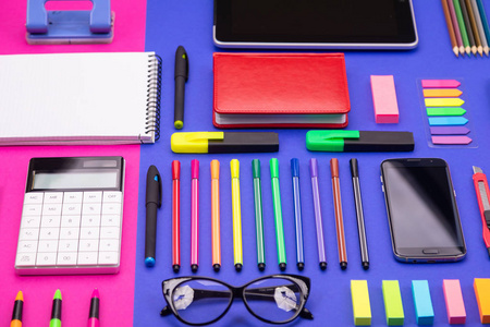 商务办公桌复合的顶部视图与智能手机, 计算器, 贴纸, 和彩色钢笔粉红色和蓝色的背景