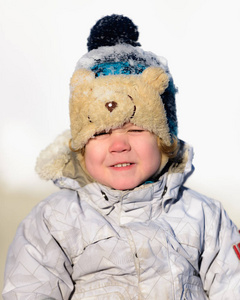 肖像小男孩在雪地里玩耍时，穿着棉袄和针织帽玩得很开心。