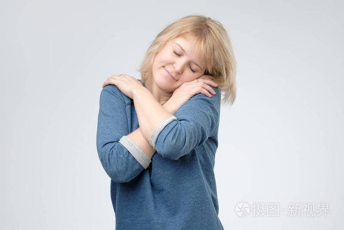迷人的女性闭上眼睛享受拥抱自己感觉舒适和舒适