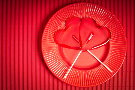 情人节背景与红色板材和两个心形棒棒糖在红色背景