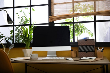 时尚的工作场所，电脑靠近窗户在家庭办公室。文本空间