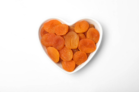 碗与干燥杏在白色背景，顶部视图。健康水果