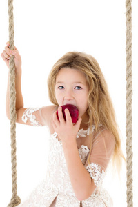 在秋千上吃苹果的小女孩