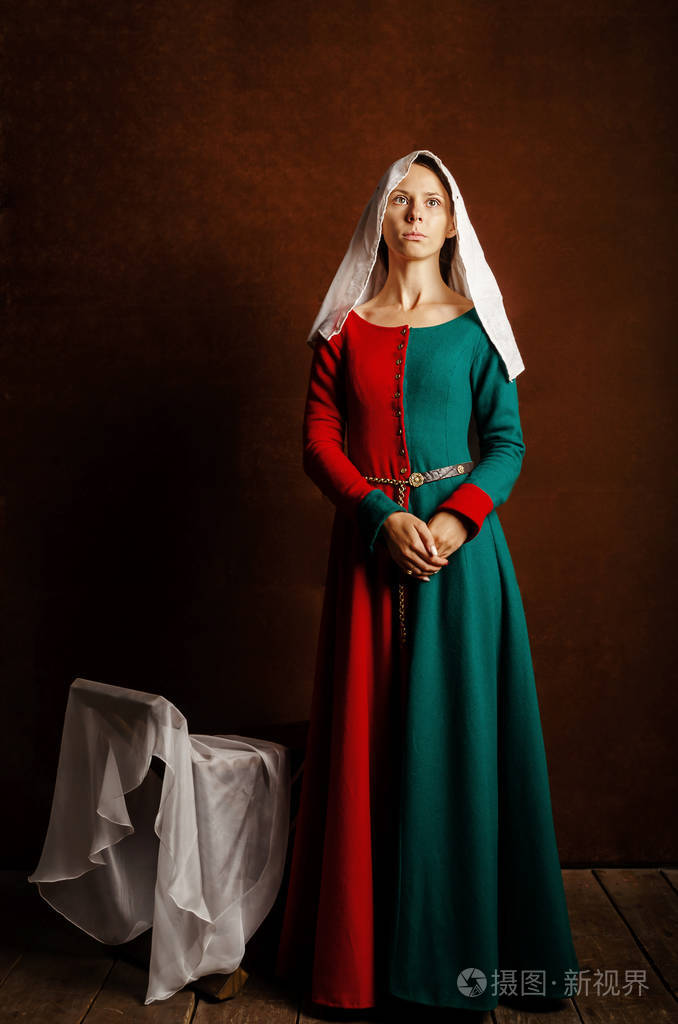 一个美丽的女孩的肖像,穿着一件中世纪的衣服,红色和绿色,棕色背景.