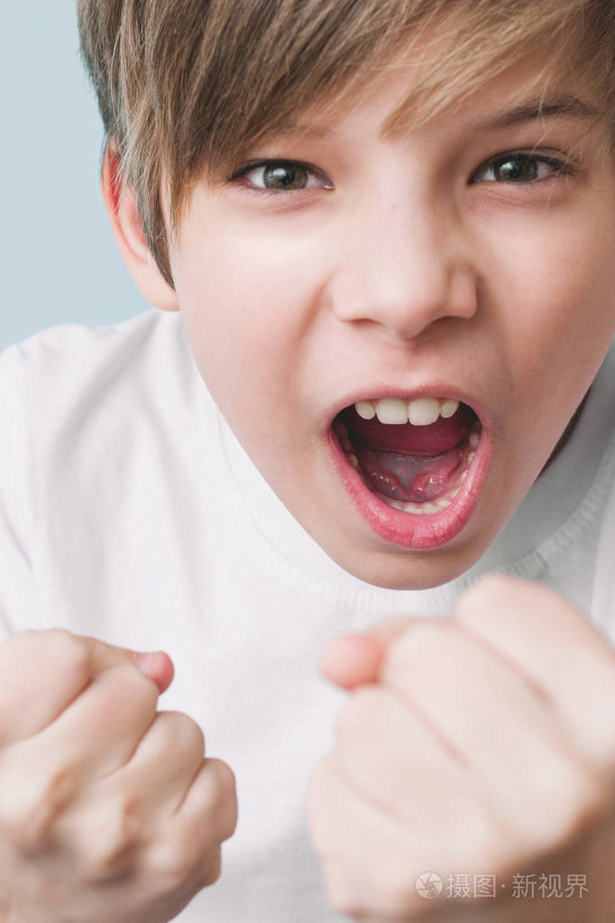 男孩尖叫着,用拳头开玩笑地威胁. 情感概念