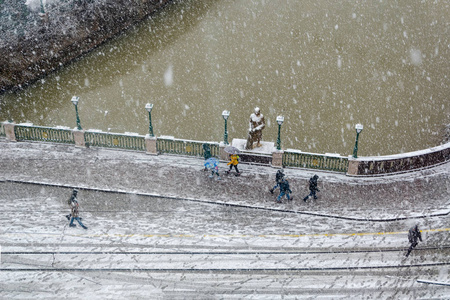 城市顶部的降雪。由于降雪，人们拿着雨伞和头巾走路。